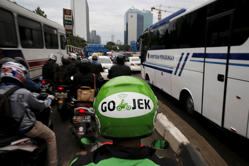 A Gojek driver rides his motorcycle through the business district of Jakarta on June 9, 2015. Jakarta's traffic jams are a constant vexation for the city's 10 million residents. The Indonesian capital's glaring inefficiencies have also created opportunities for the likes of Makarim, who has launched a smartphone app, GO-JEK, that lets users summon a motorbike rider to weave them quickly through gridlocked traffic, deliver a meal or even go shopping.