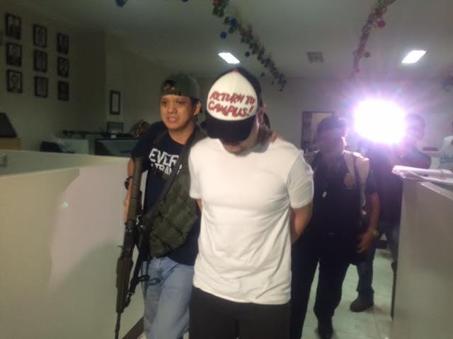 NBI agents escort De Guzman (in baseball cap covering his face). John Consulta