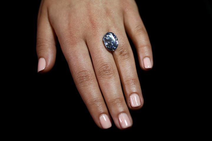 An employee disdplays a 10.10 carat internally flawless blue diamond at Sotheby's auction house in central London, Britain March 15, 2016. The oval fancy vivid blue diamond is expected to fetch between $30-35 million at the auction house's Magnificent Jewels and Jadeite auction in Hong Kong on April 5. Photo: REUTERS/Stefan Wermuth