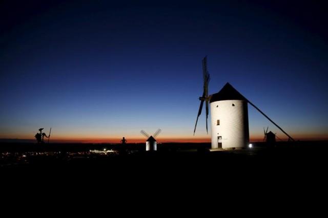 Sculptures of Don Quixote (L) and his ladyship Dulcinea (C) are seen at dusk by the windmills of Mota del Cuervo, Spain, April 6, 2016. Photo: Susana Vera/Reuters