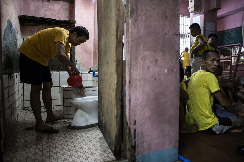 An inmate cleans the toilet at the Quezon City Jail in this picture taken on July 29, 2016. There are 3,800 inmates at the jail, which was built six decades ago to house 800, and they engage in a relentless contest for space. Men take turns to sleep on the cracked cement floor of an open-air basketball court, the steps of staircases, underneath beds and hammocks made out of old blankets. NOEL CELIS/AFP