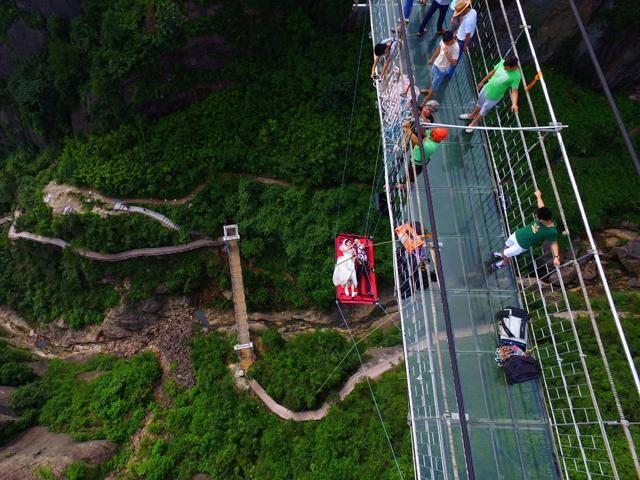 A newly married couple lie on a canvas mat as they are lowered from a glass bridge during a promotional event for the tourist spot, on Chinese Valentines' Day in Pingjiang, Hunan province, China, August 9, 2016. Picture taken August 9, 2016. China Daily/via REUTERS 