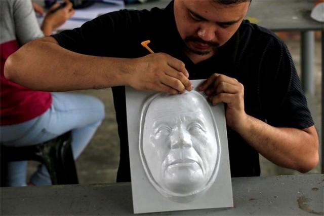 Industrial engineer and professor John Tan uses a cutter to trim an unfinished Halloween mask depicting President Rodrigio Duterte at the College of Fine Arts of the University of the Philippines in Quezon City. PHOTO: REUTERS/Romeo Ranoco.