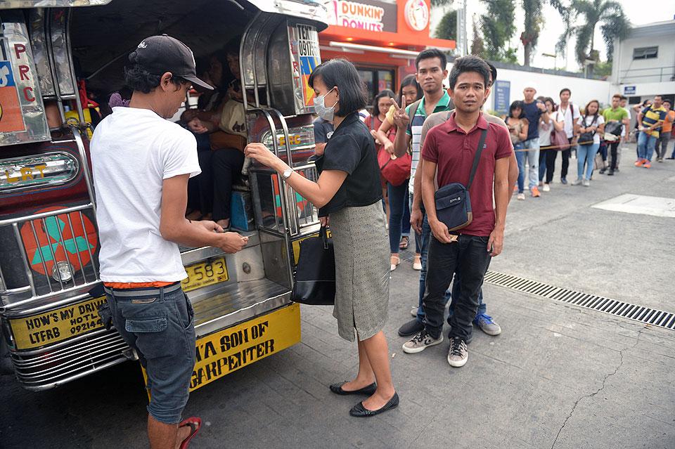Commuters fall in line to ride a jeepney in Makati City in this photo taken on May 3, 2017. The jeepney, once hailed as the 'King of the Road' and a cultural symbol in the Philippines to rival New York's yellow taxis, may soon disappear from Manila's gridlocked streets as authorities move to phase out the iconic World War II-era vehicle, citing pollution and safety concerns. AFP/Ted Aljibe
