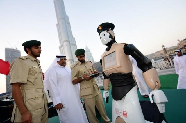 The world's first operational police robot stands to attention near the Burj Khalifa in Downtown Dubai on May 31, 2017, as a military cannon is prepared to be fired at sunset marking the end of the fasting day for Muslims observing Ramadan. After bringing in Lamborghinis and Ferraris to patrol roads, Dubai police have enrolled a robotic officer, the first in a unit that aims to make up a quarter of the force by 2030. AFP