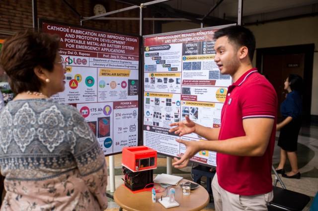 Audrey Dei O. Raposa, a chemical engineering student, describing the mechanics of his portable metal-air battery system prototype to judge Engr. Rosario Calderon of the UP ERDFI