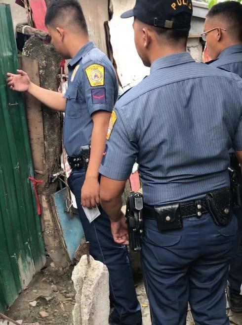 Policemen from QCPD Station 6 knock on a makeshift gate in Lupang Pangako, Payatas as they conduct drug testing operations. Luz Rimban/VERA Files