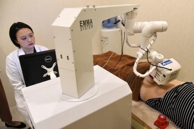 In this photo taken on October 12, 2017, a Singaporean physician monitors progress as robot masseuse 'Emma' massages a patient at the NovaHealth traditional chinese medicine (TCM) clinic in Singapore. Roslan Rahman/AFP