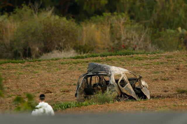 A forensics expert walks in a field after a powerful bomb blew up a car (Rear) killing investigative journalist Daphne Caruana Galizia in Bidnija, Malta, October 16, 2017. REUTERS/Darrin Zammit Lupi 