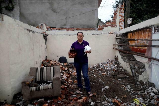 Maria Trinidad Gonzalez, 41, holds some cookware, whih she said are the most valuable things that she recovered, as she stands amid the rubble of her house after an earthquake hit Tepalcingo, Mexico, September 29, 2017.She lives in her backyard and hopes to return home once it's rebuilt. REUTERS/Edgard Garrido
