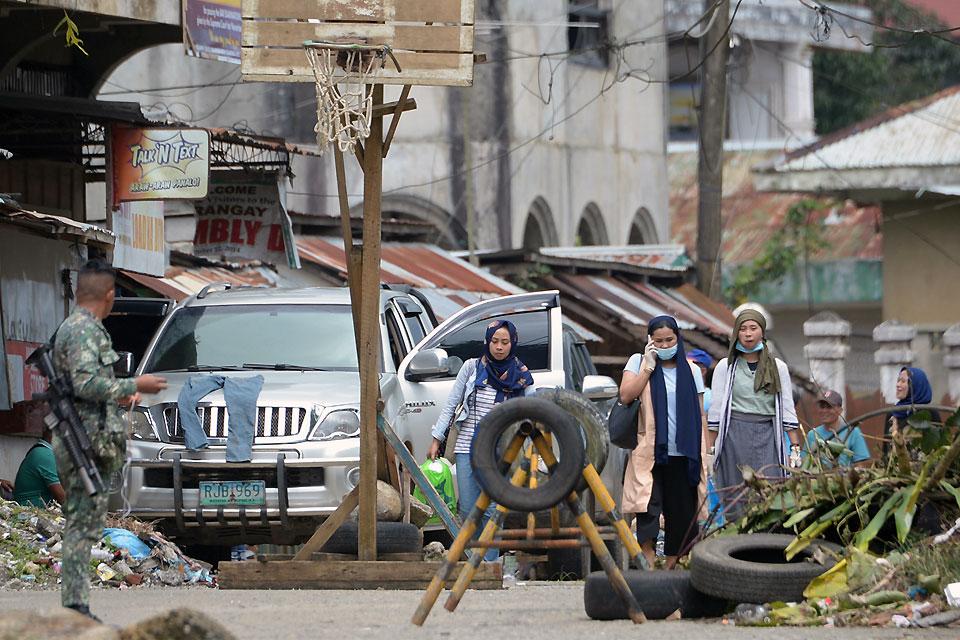 A soldier keeps watch as residents returning to inspect their homes walk past near the main battle area of Mapandi in Marawi City on Tuesday, October 24, 2017, a day after the military declared the fighting over. AFP/Ted Aljibe 