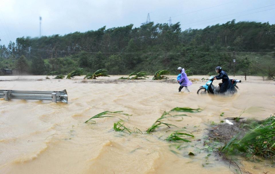 This picture taken on November 4, 2017 shows people walking through floodwaters on a highway in the central province of Dak Lak brought by Typhoon Damrey. At least 19 people have died and a dozen are missing after Typhoon Damrey barrelled into Vietnam, authorities said on November 5, just days before the country welcomes world leaders to the APEC summit. STR/Vietnam News Agency/AFP