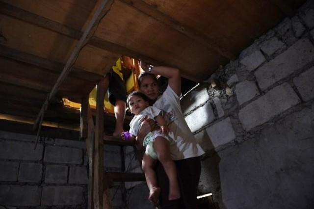 This photo taken on October 10, 2017 shows Myrna Albos, 33, carrying her child as she walks down to their house in a slum area in Manila. 