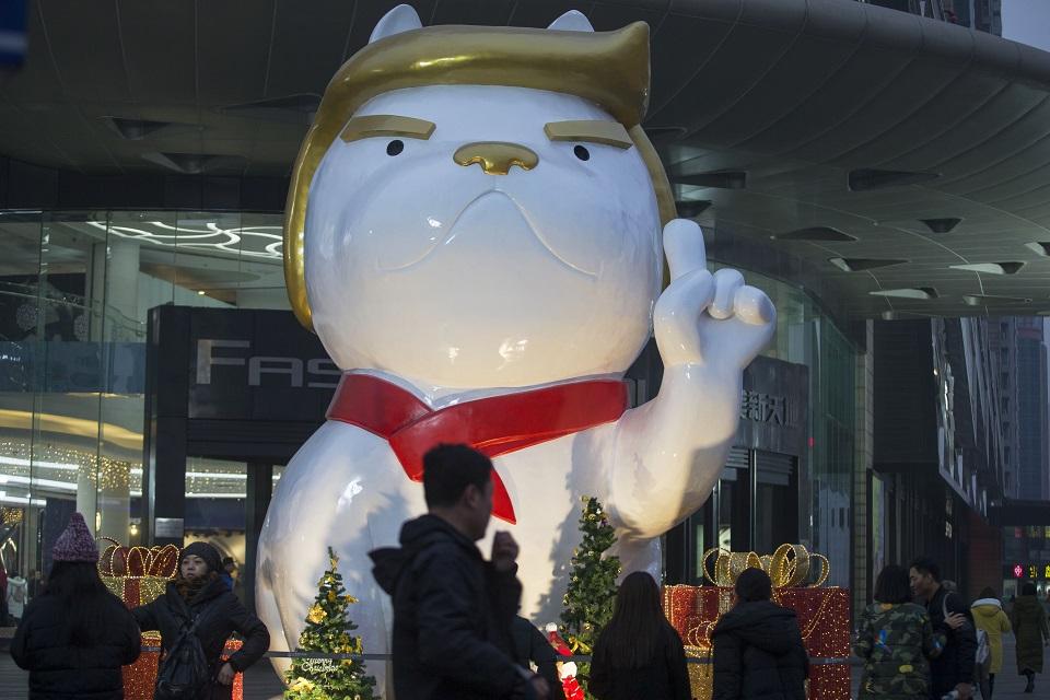 People walk past a statue of a dog, with a resemblance to US President Donald Trump, outside a shopping mall in Taiyuan, in China's northern Shanxi province on December 29, 2017. STR/AFP