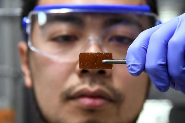 In this picture taken on December 25, 2017, Yu Yanagisawa, a chemistry researcher at the University of Tokyo, displays a piece of repaired broken resin glass after pressing the pieces back together at the university's lab in Tokyo. Toru Yamanaka/AFP