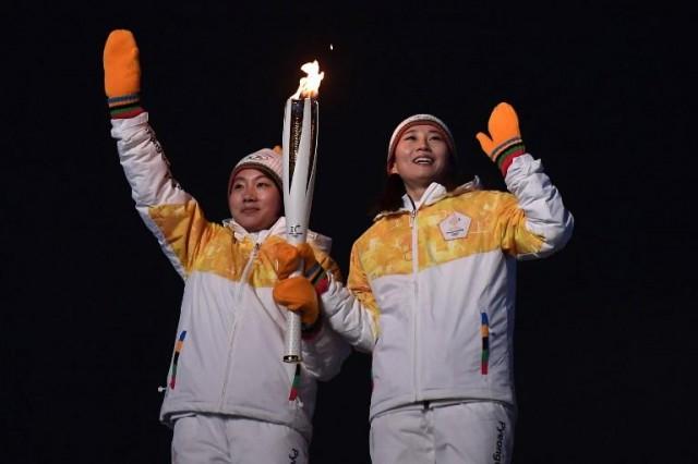 Unified Korea torchbearers, North Korean Jong Su Hyon and South Korean Park Jong-ah hold the Olympic Flame before the lighting of the cauldron during the opening ceremony of the Pyeongchang 2018 Winter Olympic Games at the Pyeongchang Stadium on February 9, 2018. ARIS MESSINIS / AFP