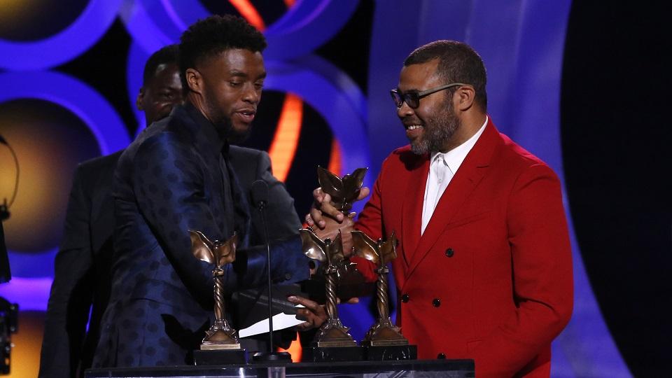 Actor Daniel Kaluuya (rear, obscured) watches as director Jordan Peele (R) receives the Best Feature Award for the film "Get Out" from presenter Chadwick Boseman. REUTERS/Mario Anzuoni