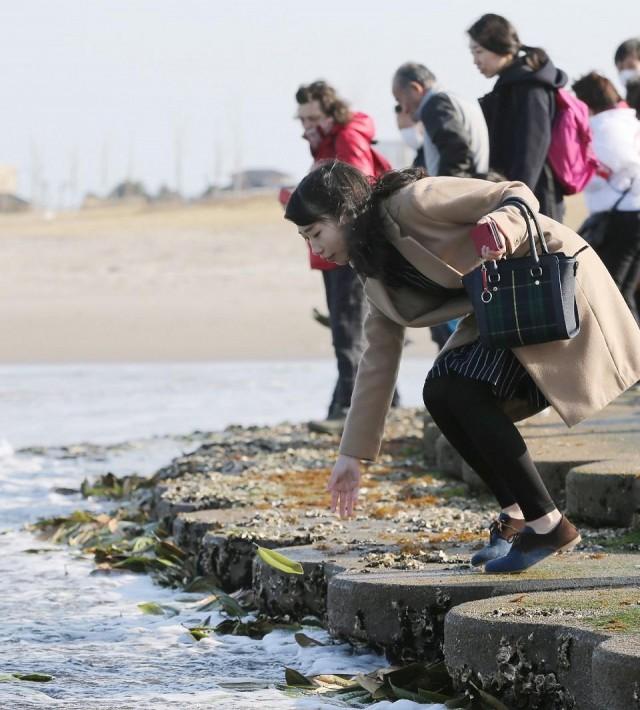 A woman places a leaf with a message for victims of the 2011 earthquake, tsunami and nuclear disaster, which devastated Japan's northeastern coast and left about 18,500 people dead or missing, in Soma City, Fukushima prefecture on March 11, 2018. Jiji Press/AFP