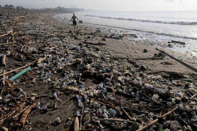 A resident walks along a section of Matahari Terbit beach covered in plastic and other debris washed ashore by seasonal winds near Sanur, Bali, Indonesia April 11, 2018. REUTERS/Johannes P. Christo