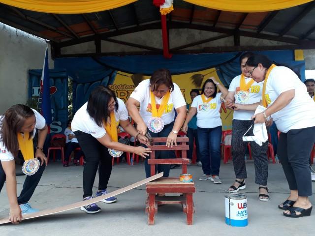 Negros Oriental Schools Division Superintendent Wilfreda Bongalos, center, hammers a chair during the launch of the Brigada Eskwela in the province on Monday. Photo by Raffy Cabristante