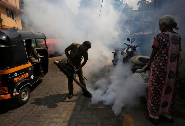A municipal worker fumigates a manhole in a street to prevent the spread of dengue fever and other mosquito-borne diseases in Mumbai, India, May 24, 2018. REUTERS/Francis Mascarenhas