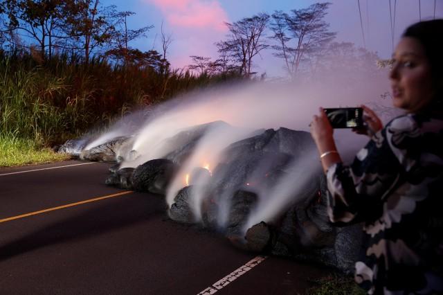 A news reporter takes pictures of the Kilauea lava flow that crossed Pohoiki Road near Highway 132, near Pahoa, Hawaii, U.S., May 28, 2018. REUTERS/Marco Garcia