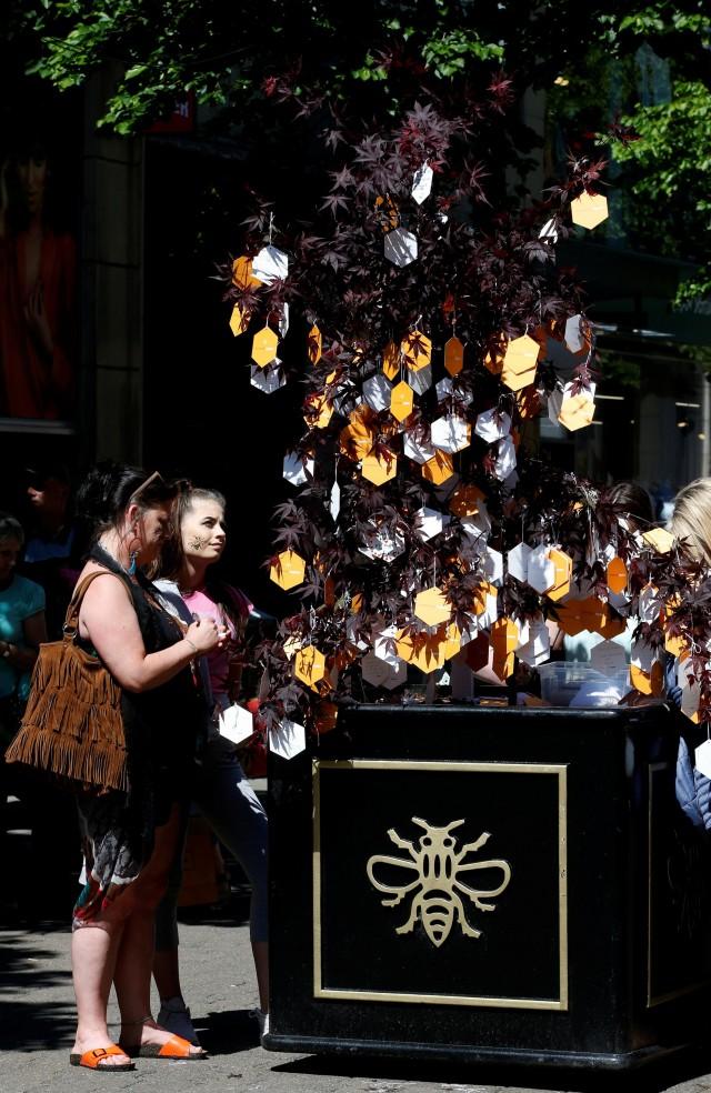 People look at tributes left on a tree in St Anne's Square on the first anniversary of the Manchester Arena bombing, in Manchester, Britain, May 22, 2018. REUTERS/Andrew Yates