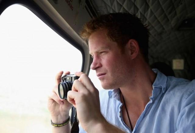 In this file photo taken on December 08, 2014 Britain's Prince Harry takes a photograph out of the window of a Lesotho Army Helicopter as he travels over the Muluti Mountains on the way to a herd boy night school constructed by Sentebale in Mokhotlong, Lesotho, on December 8, 2014. AFP PHOTO / POOL / CHRIS JACKSON