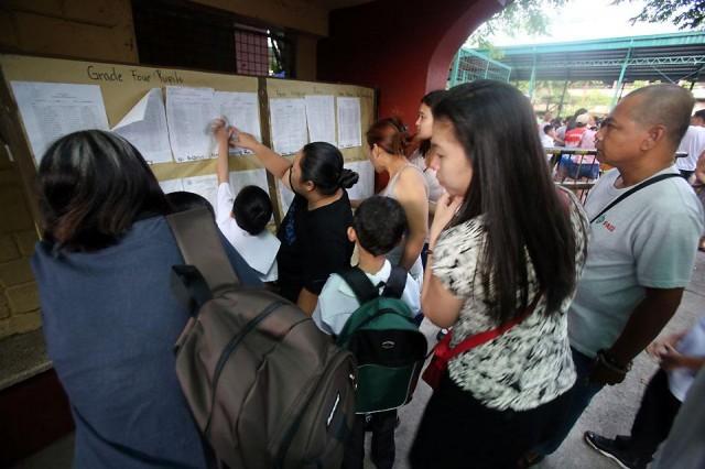 A common scene during first day of classes: Parents and guardians searching for the room assignment of their children.