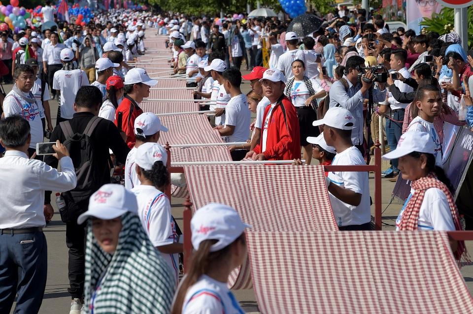 Thousands of young people rolled out the krama along a street in the capital Sunday for a visiting Guinness official to measure the garment. Tang Chhin Sothy/AFP