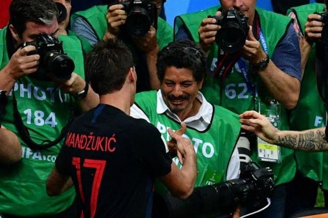 Croatia's forward Mario Mandzukic (L) shakes hands with AFP photographer Yuri Cortez (C) after falling on him with teammates while celebrating their second goal during the Russia 2018 World Cup semi-final football match between Croatia and England at the Luzhniki Stadium in Moscow on July 11, 2018. Mladen Antonoc/AFP