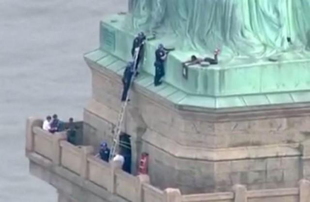 This still image taken from video Courtesy of PIX11 News in New York, shows police (L) talking to a woman who climbed to the base of the Statue of Liberty in New York on July 4, 2018. Jose ROMERO / PIX11 News / AFP
