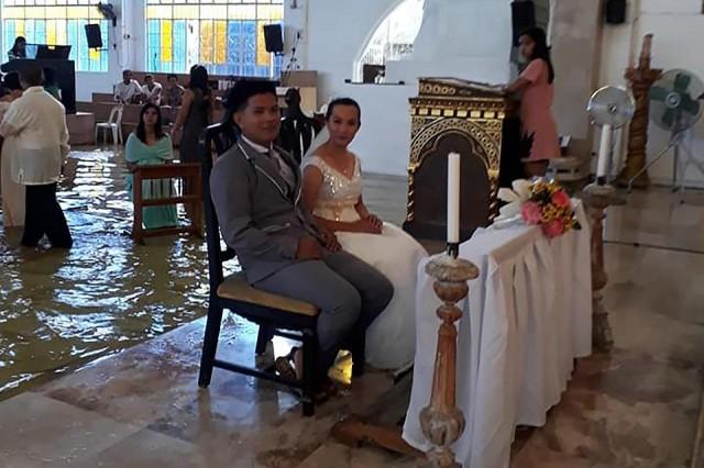 This handout photo taken from the Facebook account of Bautista Banares Tere on August 11, 2018 shows the bride Jobel Delos Angeles, 24, and her groom during their wedding amidst a flooded church in Hagonoy town, Bulacan, on August 11, 2018. Bautista Banares Tere/AFP