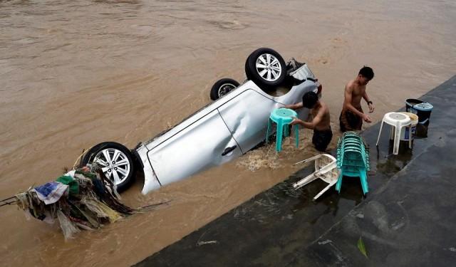 Residents wash chairs next to a submerged vehicle after flashfloods brought by continuous monsoon rains in Marikina, Metro Manila, August 12, 2018. REUTERS/Erik De Castro
