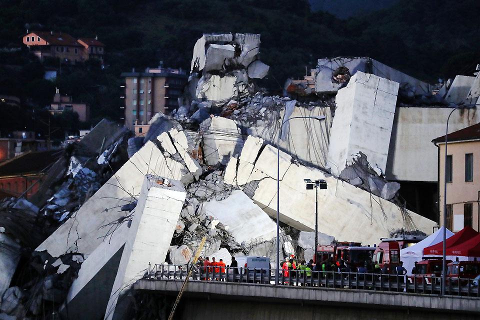 Rescuers inspect the rubble of the collapsed Morandi motorway bridge in Genoa, Italy on Tuesday, August 14, 2018. About 37 people died when the giant motorway bridge collapsed in heavy rain in what the government called an "immense tragedy." The collapse, which saw a vast stretch of the A10 freeway tumble on to railway lines in the northern port city, came as the bridge was undergoing maintenance work and as the Liguria region, where Genoa is situated, experienced torrential rainfall. AFP/Valery Hache