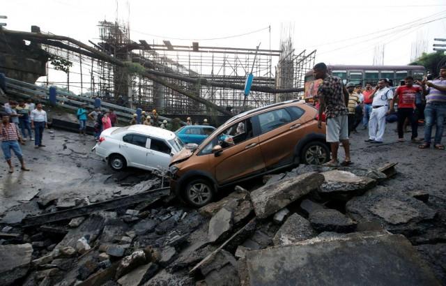People stand next to the wreckage of vehicles at the site of a bridge that collapsed in Kolkata, India September 4, 2018. REUTERS/Rupak De Chowdhuri