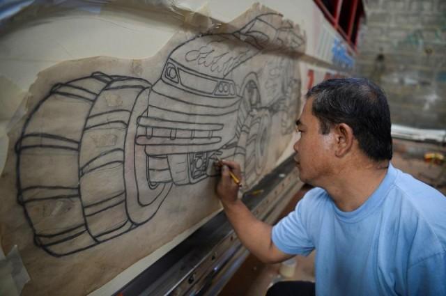 Capuno, a draftsman by education who went into jeepney painting in 1987, works along with a colleague on three or four jeepneys a month produced by San Pablo's Armak Motors. Ted Aljibe/AFP