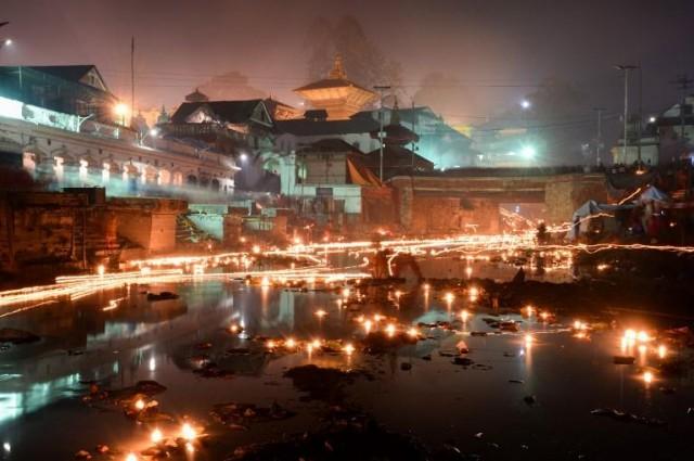 Oil lamps lit by Nepali devotees in memory of deceased family members are seen along the Bagmati river by the Pashupatinath Temple in Kathmandu during the Balachaturdashi festival on December 6, 2018. Nepali Hindu devotees light oil lamps and sow seven kinds of seeds around temple premises in the name of departed family members in observance of the festival. PRAKASH MATHEMA / AFP