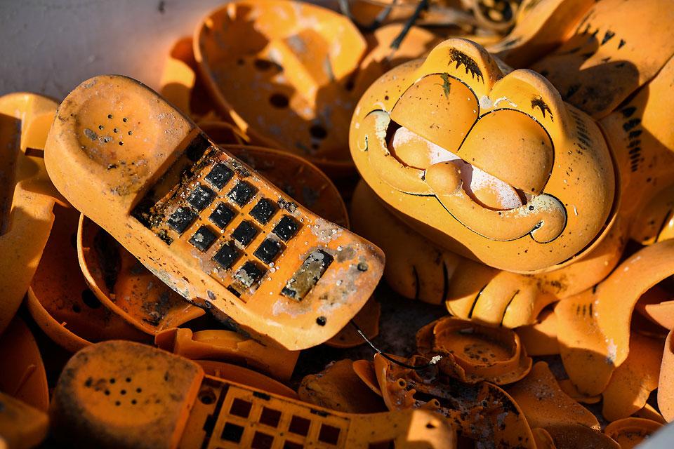 Spare parts for plastic 'Garfield' phones are seen on a beach on Thursday, March 28, 2019 in Plouarzel, western France, after being collected from a sea cave by environmental activists. For more than 30 years, plastic phones in the shape of the famous cat 'Garfield' have been washing up on French beaches. The mystery is now solved : a shipping container which washed up during a storm in the 1980s, was found in a hidden sea cave. AFP/Fred Tanneau