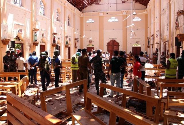 Sri Lankan security personnel walk through debris following an explosion in St Sebastian's Church in Negombo, north of the capital Colombo, on April 21, 2019. STR/AFP