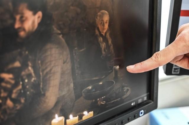 An illustration dated May 6, 2019 shows an editor in a Washington, DC newsroom pointing at a cup sitting on a table on the set of a scene with Daenerys Targaryen (R) and John Snow during the last episode of Game of Thrones which aired the previous night. STF / AFP