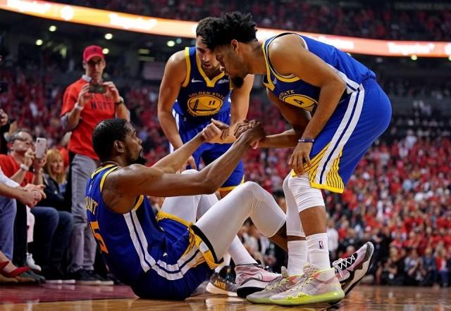 Golden State Warriors forward Kevin Durant (35) is helped up by guard Quinn Cook (4) and guard Klay Thompson (11) after an apparent injury during the second quarter in game five of the 2019 NBA Finals against the Toronto Raptors at Scotiabank Arena in Toronto on June 10, 2019. Kyle Terada-USA TODAY Sports