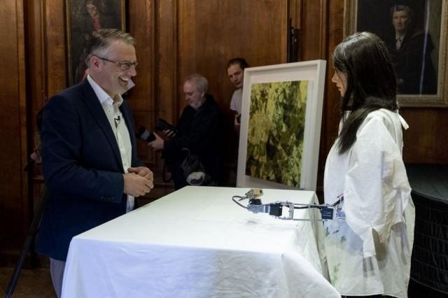 Gallery owner and creator Aidan Meller (L) talks to Ai-Da the AI humanoid robot artist (R) as it draws a portrait of him during a demonstration at a launch event for its first solo exhibition in Oxford on June 5, 2019.Ai-Da -- named after Ada Lovelace, the English mathematician and writer often called the world's first computer coder -- is able to draw creatively thanks to in-built artificial intelligence (AI) technology. Niklas HALLE'N / AFP 