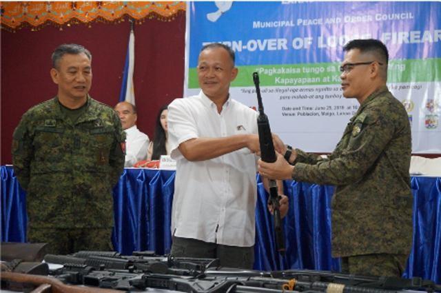 Lieutenant Colonel Rolando Oregon, 5th Mechanized Infantry Battalion Commander (right), receives firearms from Mayor Rafael Rizalda (center) while Maj. Gen Roberto Ancan, 1st ID chief (left) looks on during the turnover ceremony.