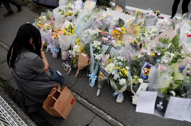 A woman prays in front of a row of flowers placed for victims of the torched Kyoto Animation building in Kyoto, Japan, July 20, 2019. REUTERS/Kim Kyung-Hoon