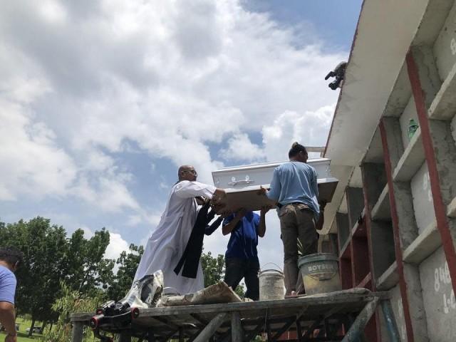 A priest helps place the small coffin of 3-year-old Myca Ulpina in its final resting place at the Forest Lawn Memorial Park in Rodriguez, Rizal on Tuesday, July 9, 2019. Dano Tingcungco