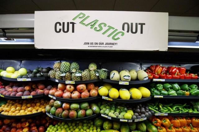 A sign promoting plastic free packaging is seen above a display of loose fresh fruit at Budgens supermarket in Belsize Park, north London on July 2, 2019. TOLGA AKMEN / AFP