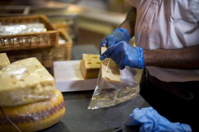 A member of staff uses cellulose plastic-free packaging to prepare a portion of cheese for sale at Budgens supermarket in Belsize Park, north London on July 2, 2019. TOLGA AKMEN / AFP