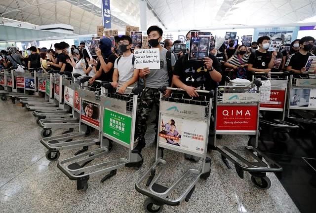 Anti-government protesters stand at a barricade made of trolleys during a demonstration at Hong Kong Airport, China August 13, 2019. REUTERS/Issei Kato