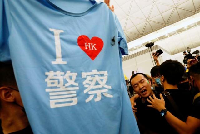 A tee shirt where it reads &acirc;I love Hong Kong police&acirc; is found in the bag of Fu Guohao (C), reporter of Chinese media Global Times website, during a mass demonstration at the Hong Kong international airport, in Hong Kong, China, August 13, 2019. REUTERS/Tyrone Siu